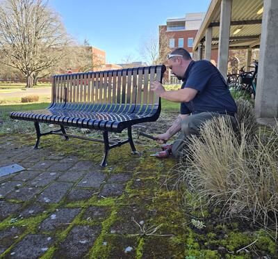 A man hammers a bench into place.