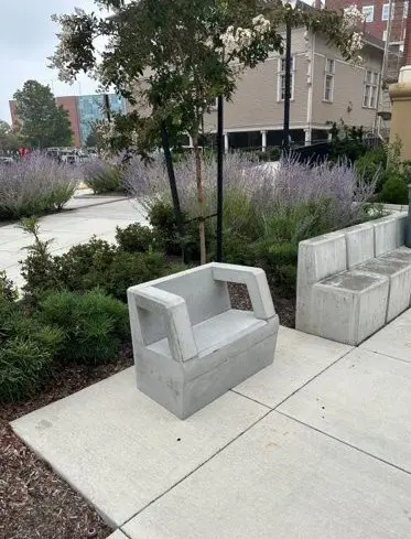 A concrete bench sitting in a garden area. 
