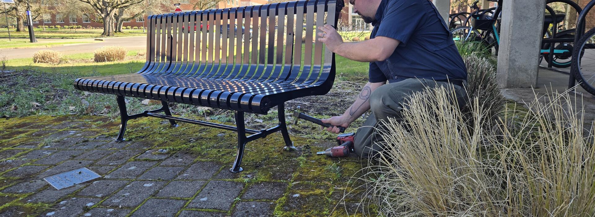 A man hammers a bench into place.