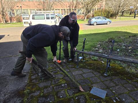Two men taking apart an old bench. 