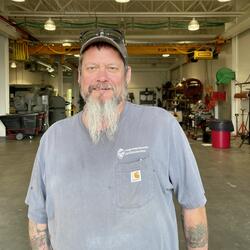 Man with hat, handle bar goatee and light blue t-shirt 