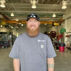 Man with hat, curly red beard and gray t-shirt