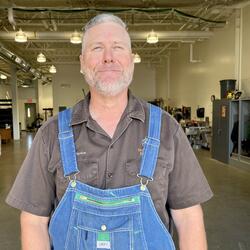 Ted wearing a brown short sleeve shirt and blue overalls